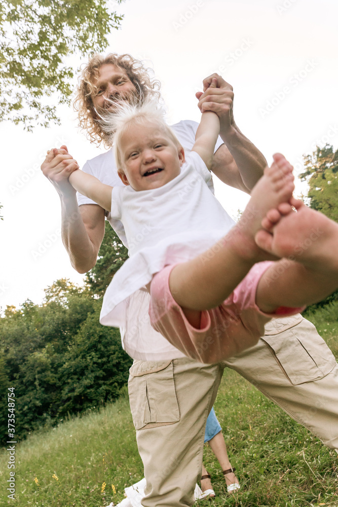 Fototapeta premium Father and daughter playing on the grass at the day time. Concept of friendly family.