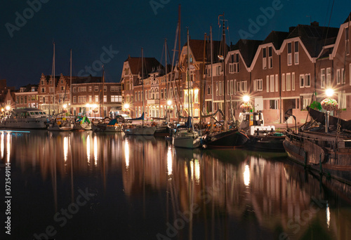  dutch houses with boats reflected on the water of a canal in the night. Typical cityscape of North Holland, Netherlands. 