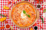 Pizza Carbonara with bacon, egg, parmesan cheese, fresh basil and tomatoes sauce on a wooden board, rustic village background, top view. European and American cuisine