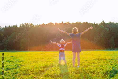 Teenage girl and little boy open arms under the sunset  happy and family life concept