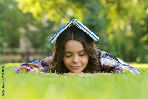 Calming book. Small child sleep on green grass. Bibliotherapy. Mindfulness and relaxation. Napping time. Back to school. Non-formal education and learning. Relaxing book for better sleep photo