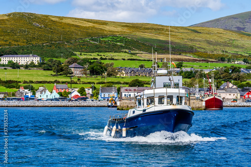 Boat tour leaving Dingle harbour for sightseeing and Fungie Dolphin watching with Dingle village in background. Co Kerry, Ireland photo