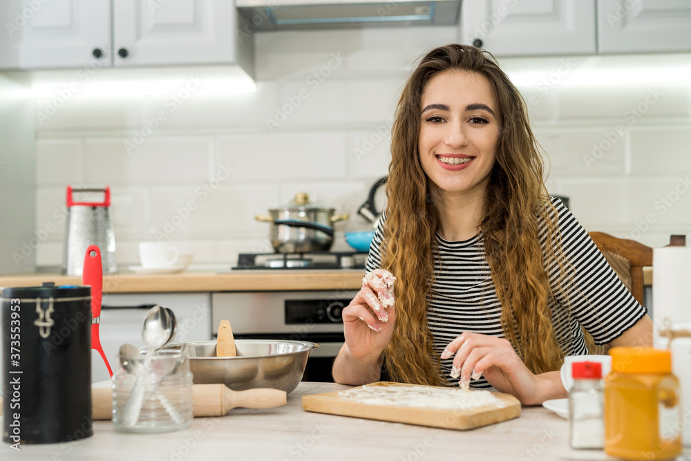 Young woman prepare delicious food knead flour on kitchen table