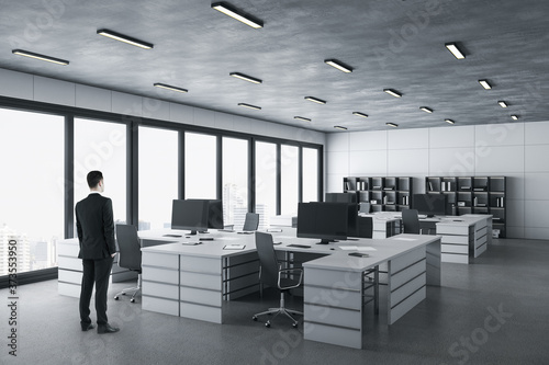 Businessman standing in in modern coworking office interior