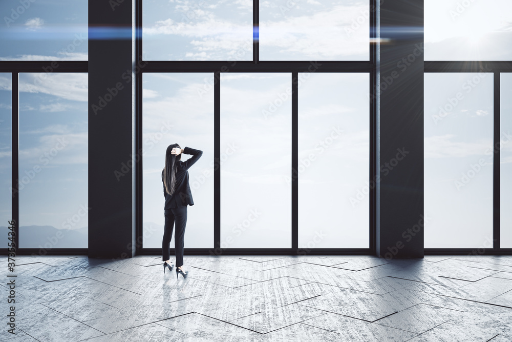 Fototapeta premium Thoughtful businesswomen standing in empty concrete hallway interior.
