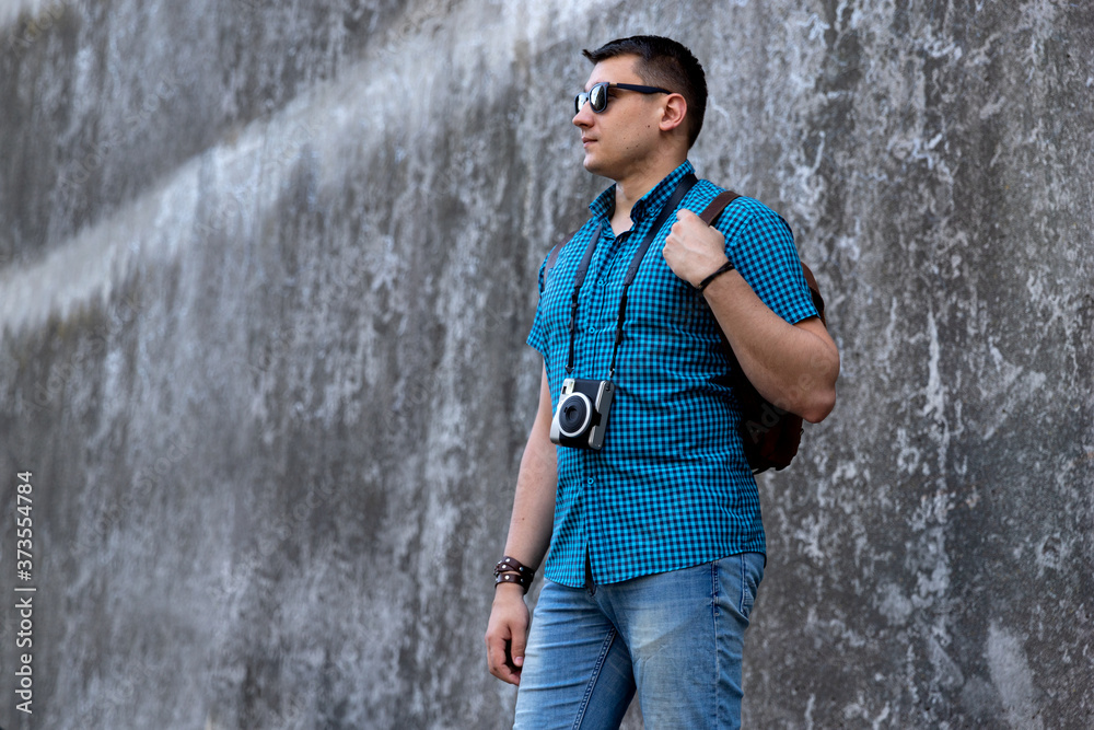 Man in casual clothes walking throught the city with camera and backpack Man in casual clothes walking throught the city with camera and backpack