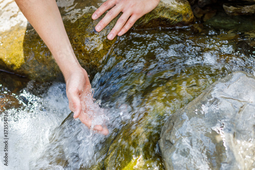 Hand is in a mountain river stream.