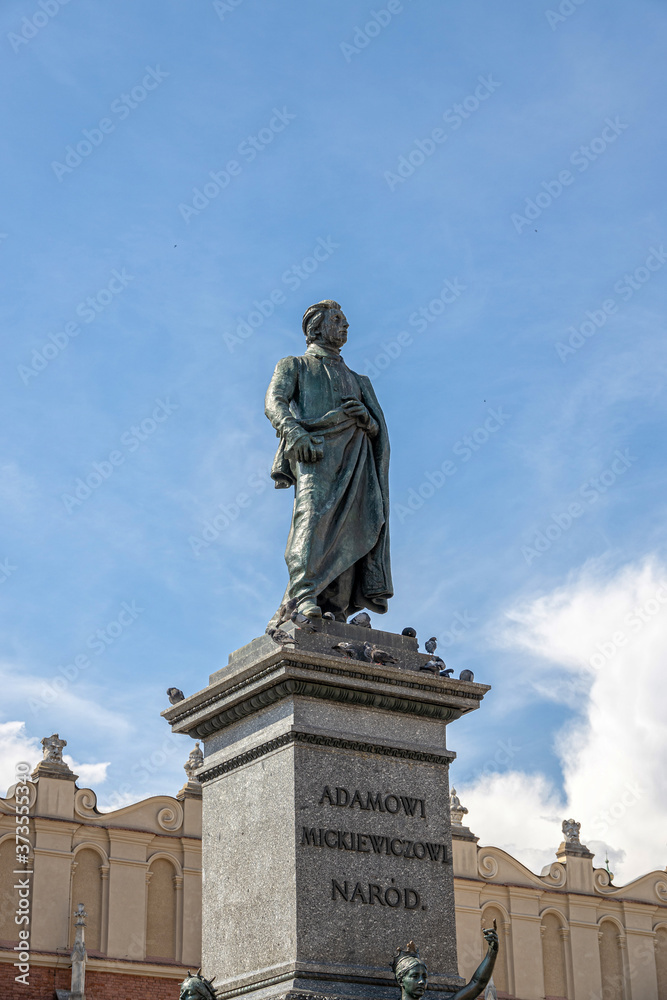  statue of Adam Mickiewicz in the Krakow market square in Poland on a summer day against the sky