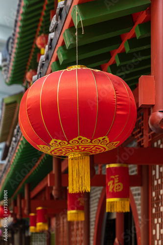 Round Chinese lantern in red on the facade of a traditional house © svetlanais