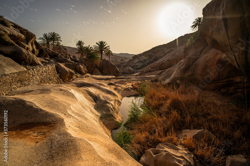 Barranco de las peñitas al atardecer con un charco y piedras de color calido photo