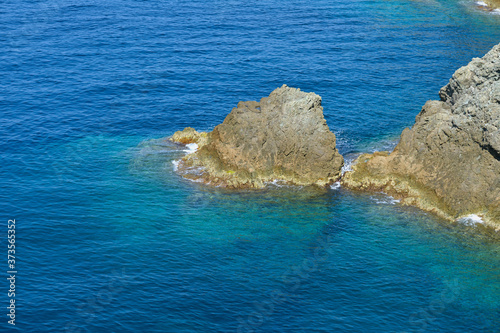 Aerial view of sea waves and fantastic Rocky coast, Italy. Rock and sea. Stone rock close up in the sea water. Clear amazing azure colour sea water with granite rocks in beach, Italy.