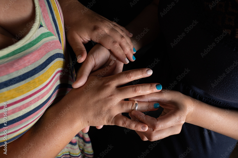 Detail of hands of Lesbian couple putting proposal ring