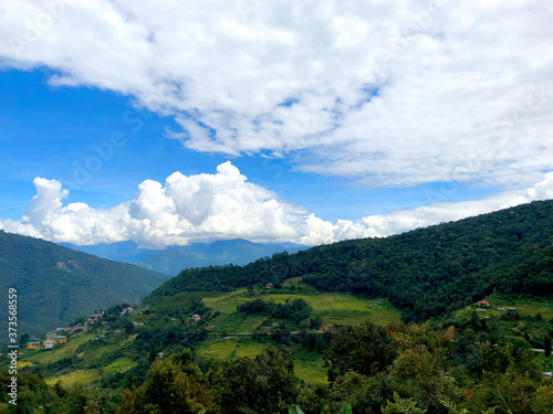 Bhutanese Countryside with Rice Paddies  Mountains  and Clouds in View