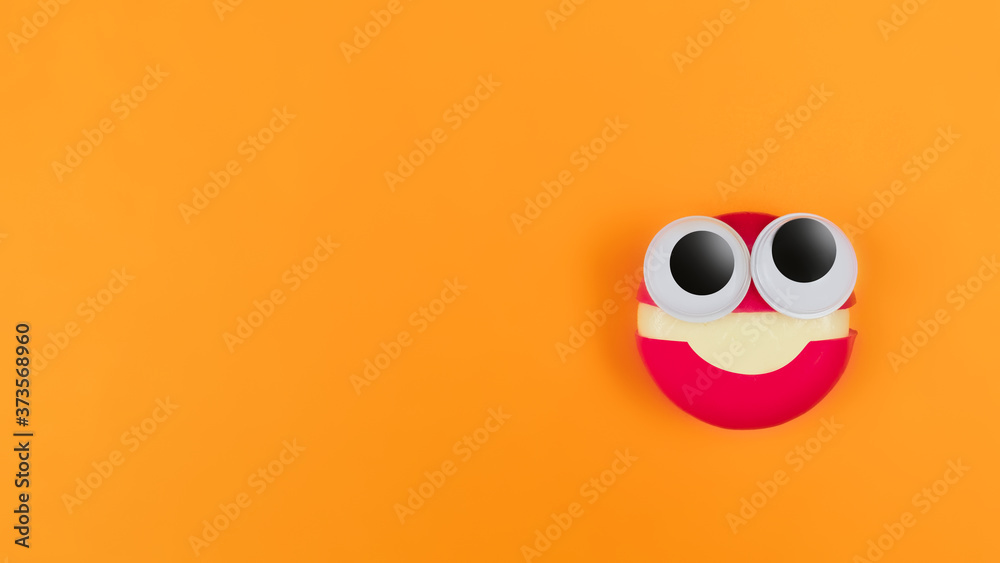 Cheese in form of little monster with eyes on orange backdrop. Halloween decor for party. Space for text. Food art