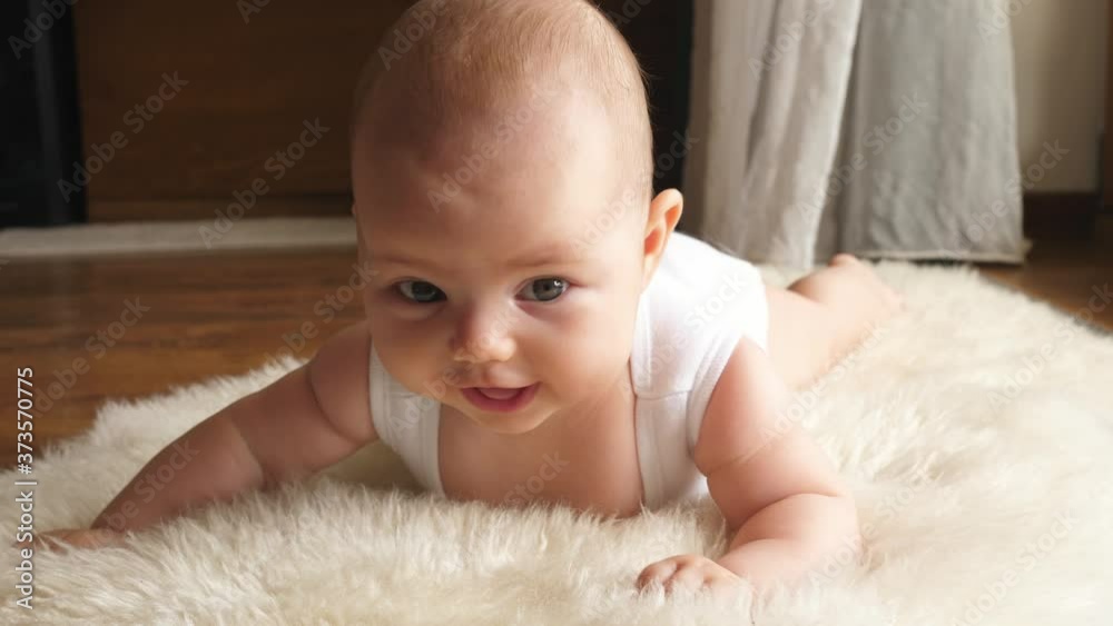 infant toddler happy cute little child lying on belly smiling to camera infant toddler happy cute little child lying on belly smiling to camera