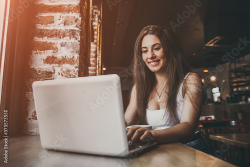 Business woman working on a laptop and drinking coffee in a cafe.