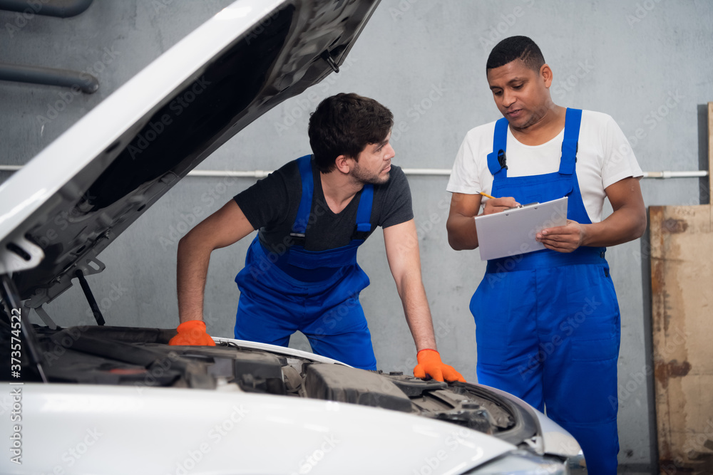 Workman gives advice to a journeyman about repairing a car Workman gives advice to a journeyman about repairing a car