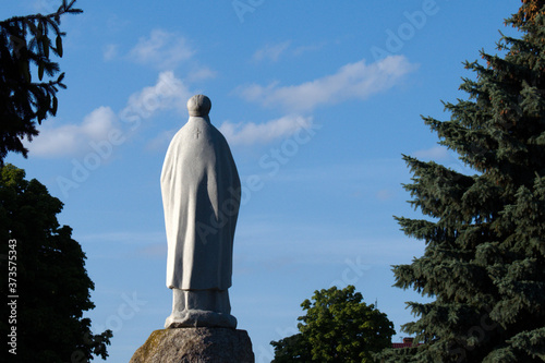 back side view of religious monument on blue sky background and green firs