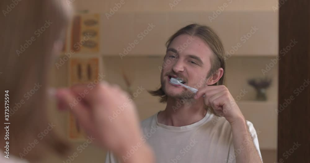 Young man looks at the mirror with happy face and dancing, brushing his teeth Young man looks at the mirror with happy face and dancing, brushing his teeth