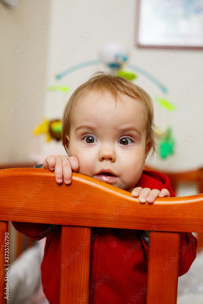 little child girl in a red sweater, smiles beautifully, in a crib, plays and has fun, emotional photo little child girl in a red sweater, smiles beautifully, in a crib, plays and has fun, emotional photo