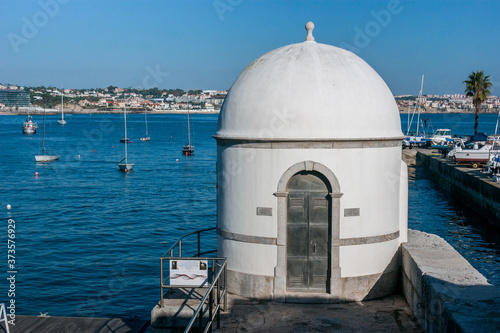 View with sun of the Cascais tide gauge in Portugal, in front of the Tagus River