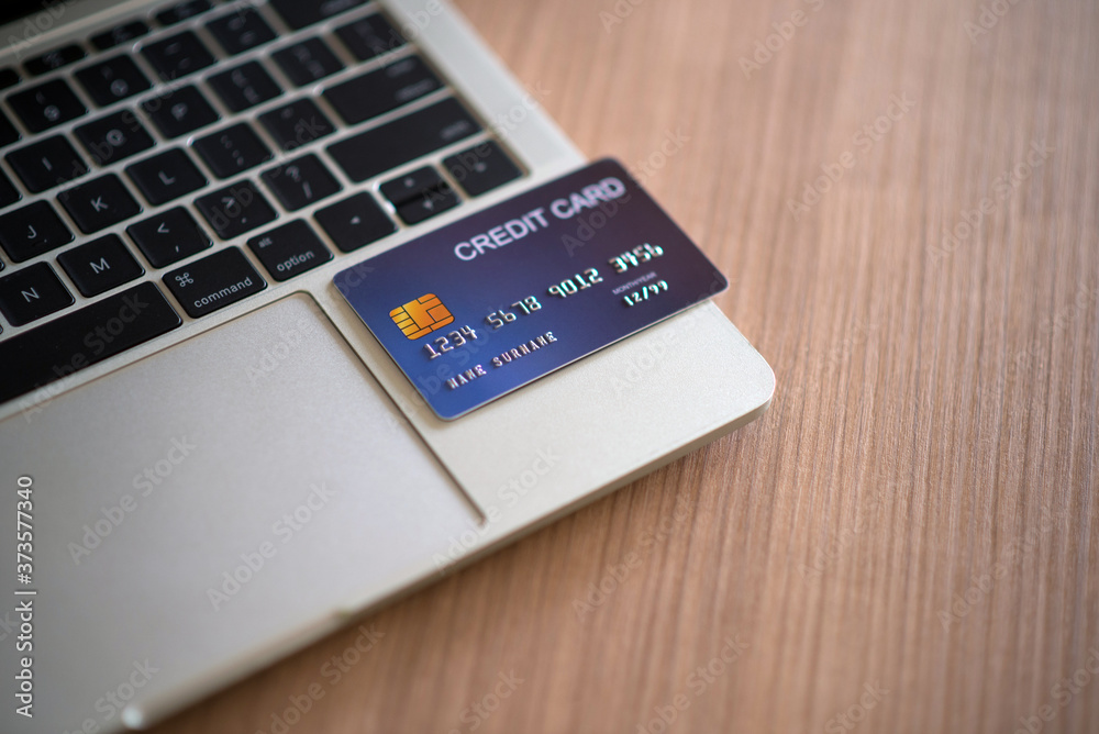 A credit card card placed on a laptop to demonstrate how fast, easy to use modern technology loan payments is the debt settlement and purchase concept. A credit card card placed on a laptop to demonstrate how fast, easy to use modern technology loan payments is the debt settlement and purchase concept.