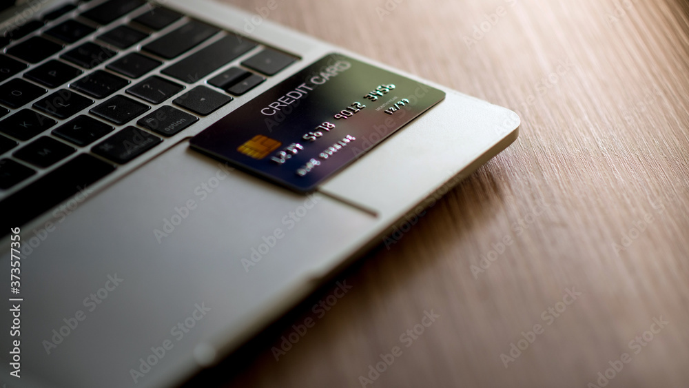 A credit card card placed on a laptop to demonstrate how fast, easy to use modern technology loan payments is the debt settlement and purchase concept. A credit card card placed on a laptop to demonstrate how fast, easy to use modern technology loan payments is the debt settlement and purchase concept.