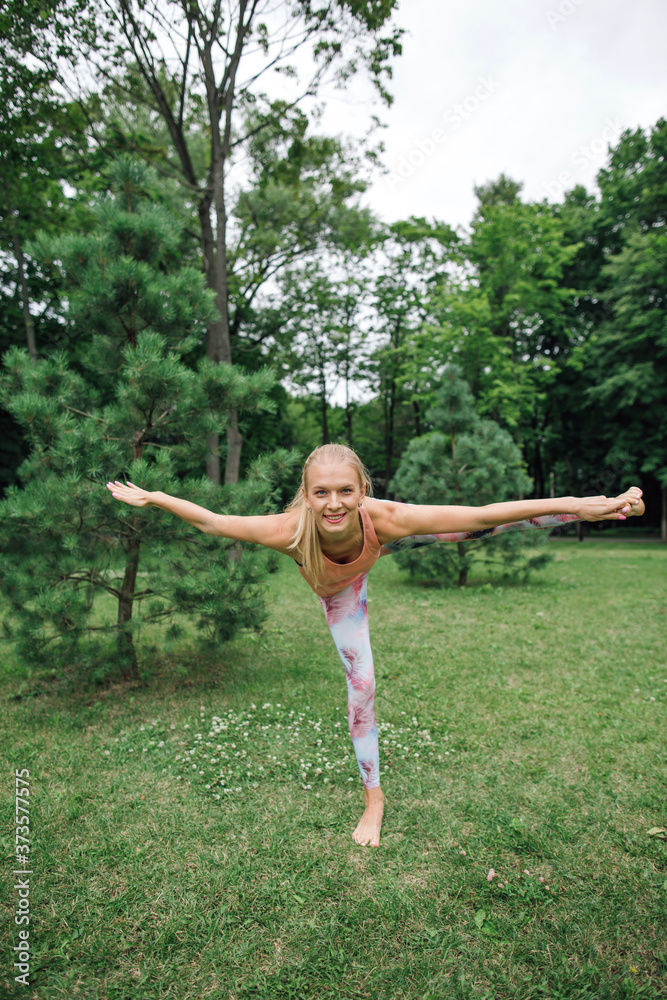 Beautiful young woman practicing yoga in the park.