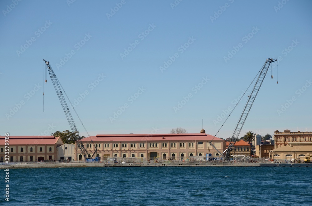 Part of the Australian Naval Base in Garden Island, Woolloomooloo with a construction crane on either side and viewed from Sydney Harbour foreshore.