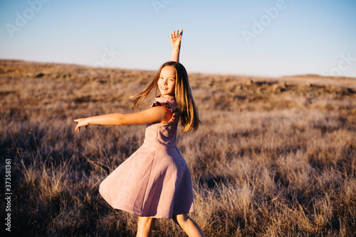 girl dancing in open field at sunset