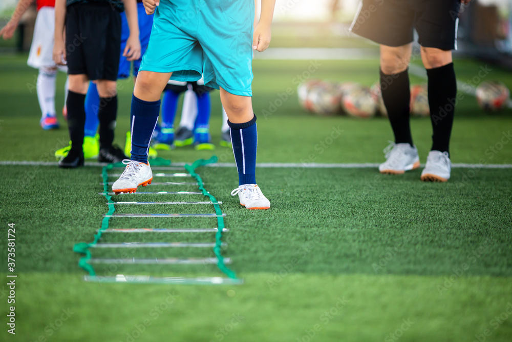 Fototapeta premium Kid soccer player Jogging and jump between marker for football training. Ladder Drills Exercises for Football team. Kid player exercises on ladder drills.