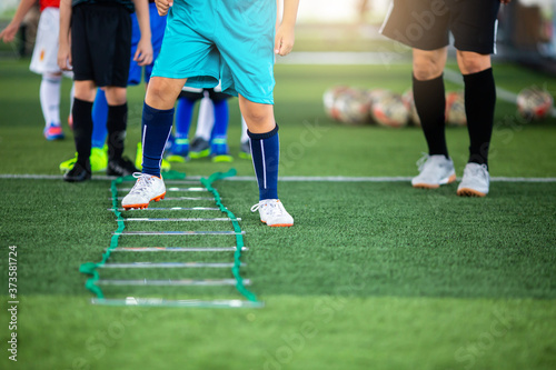 Kid soccer player Jogging and jump between marker for football training. Ladder Drills Exercises for Football team. Kid player exercises on ladder drills.