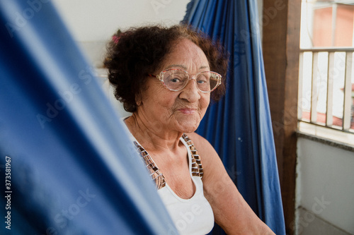 Brazilian elderly woman sitting in a hammock at home