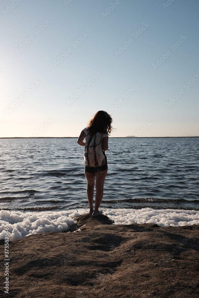 a girl with a backpack on near a lake