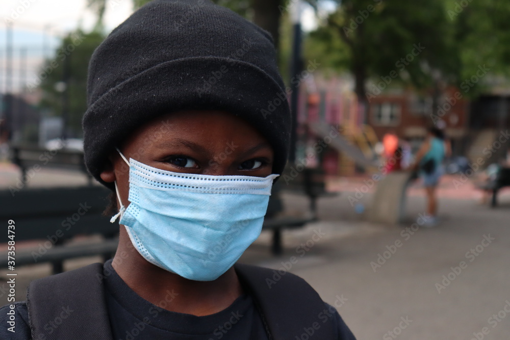 Child close up wearing surgical mask and skull cap hat outdoors Child close up wearing surgical mask and skull cap hat outdoors
