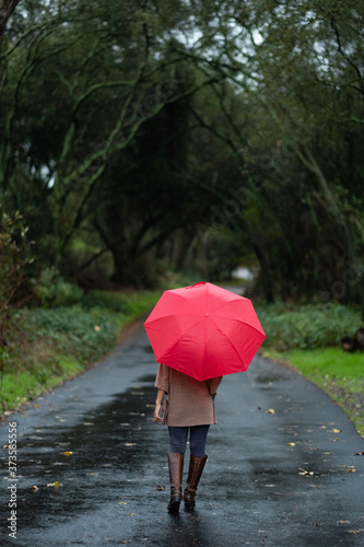 girl with red umbrella walking on a trail