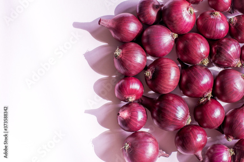 Fresh crop of red onions on a pink background. Red onion background, close-up, top view.