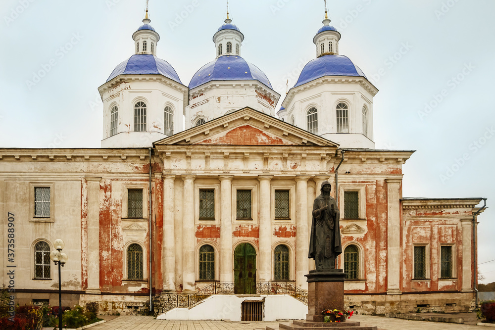 Fototapeta premium Ancient christian church and autumn yellow trees. Beautiful domes, high old bell tower against the sky
