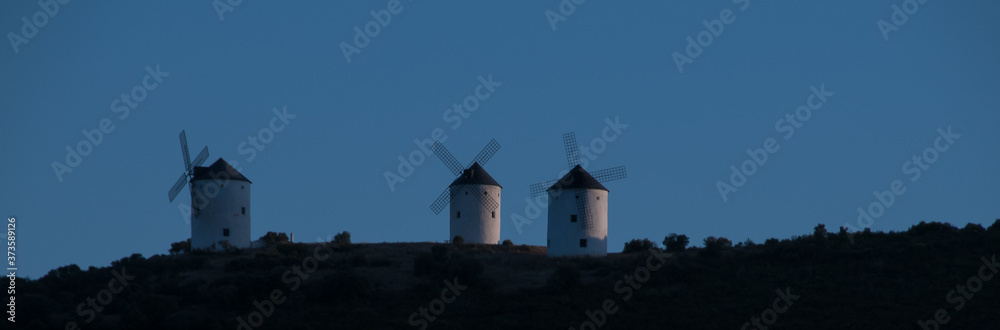 Horizonte copado por tres molinos de viento tradicionales fotografiados al atardecer en Campo de Criptana, España. Molinos con los que soñaba Don Quijote de La Mancha.