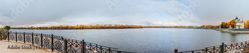Beautiful lake and yellow trees in autumn cloudy day. Panoramic landscape.
