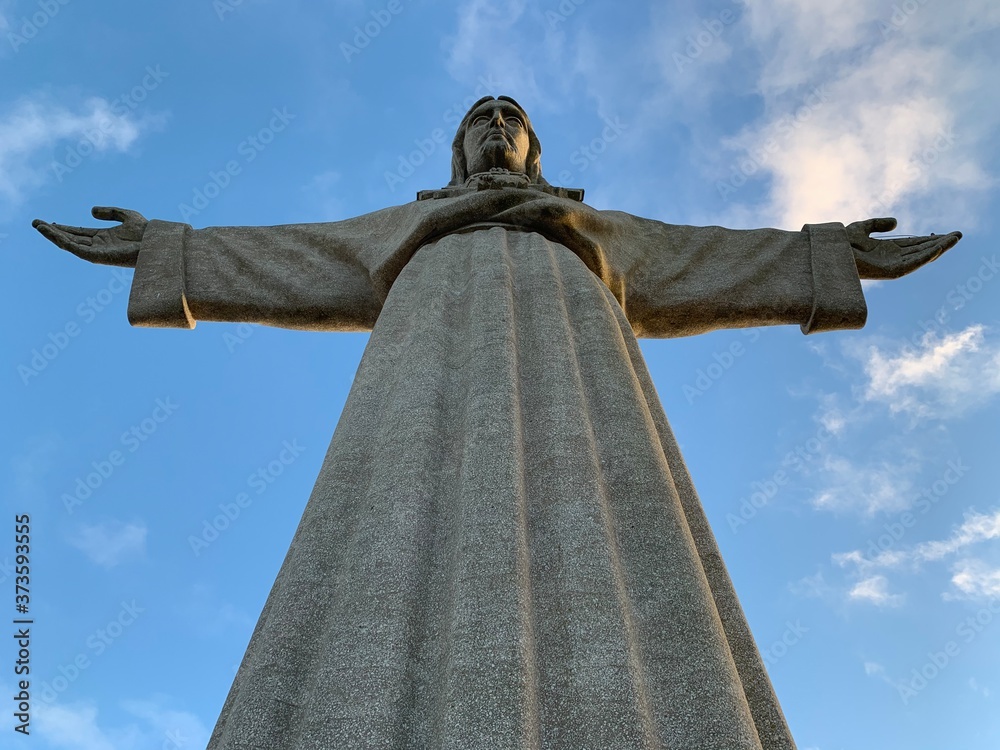 Fototapeta premium A statue of Cristo Rey and a view of the bridge named April 25 in Lisbon, Portugal.