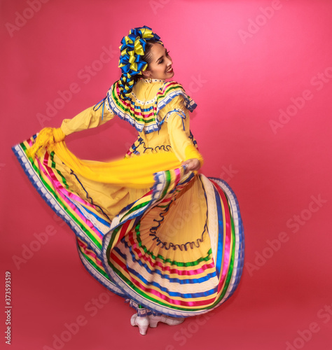 Bailarina vestida en traje tradicional folclórico mexicano amarillo en fondo rosa retrato photo