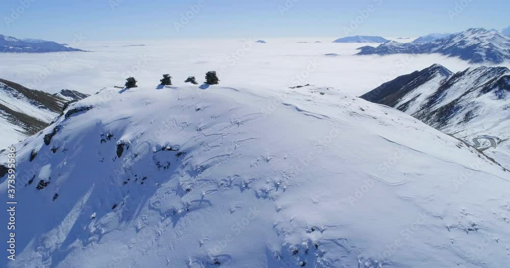 Aerial view of snow mountain range landscape under blue sky with pile of stone on the summit and sea of clouds in the background 4k winter drone footage Aerial view of snow mountain range landscape under blue sky with pile of stone on the summit and sea of clouds in the background 4k winter drone footage