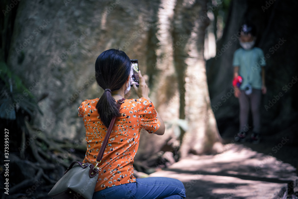 Φωτογραφία Young woman taking photo of her little son in the woods