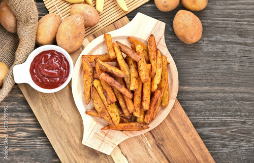 Homemade Crispy Seasoned French Fries..French fries  with spicy seasoning in wooden plate on wooden broad.