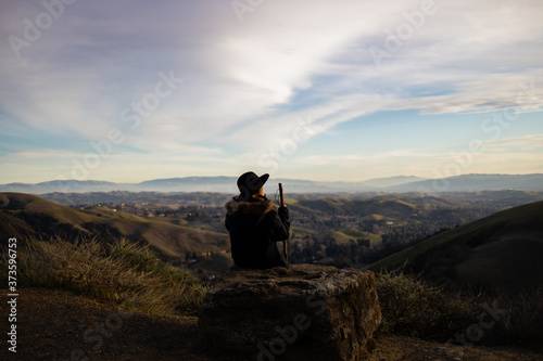 A woman in a hat with a hiking stick enjoying the views of the mountain landscape