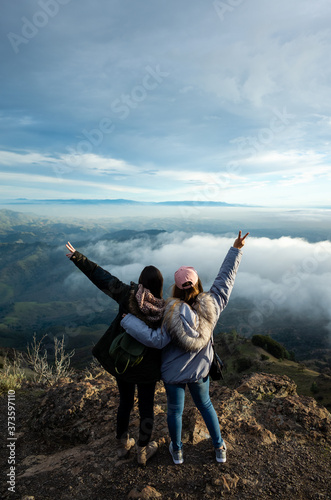 Two Women on top of a mountain with clouds and landscape views
