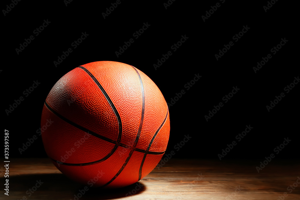 Ball for playing basketball on table against dark background