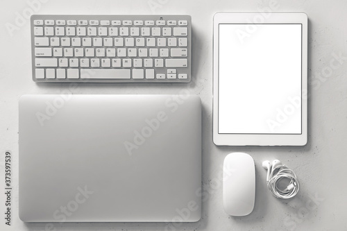 Modern laptop  keyboard  tablet computer  PC mouse and earphones on light background