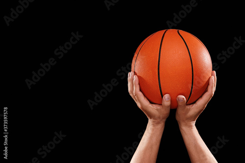 Hands of basketball player with ball on dark background © Pixel-Shot